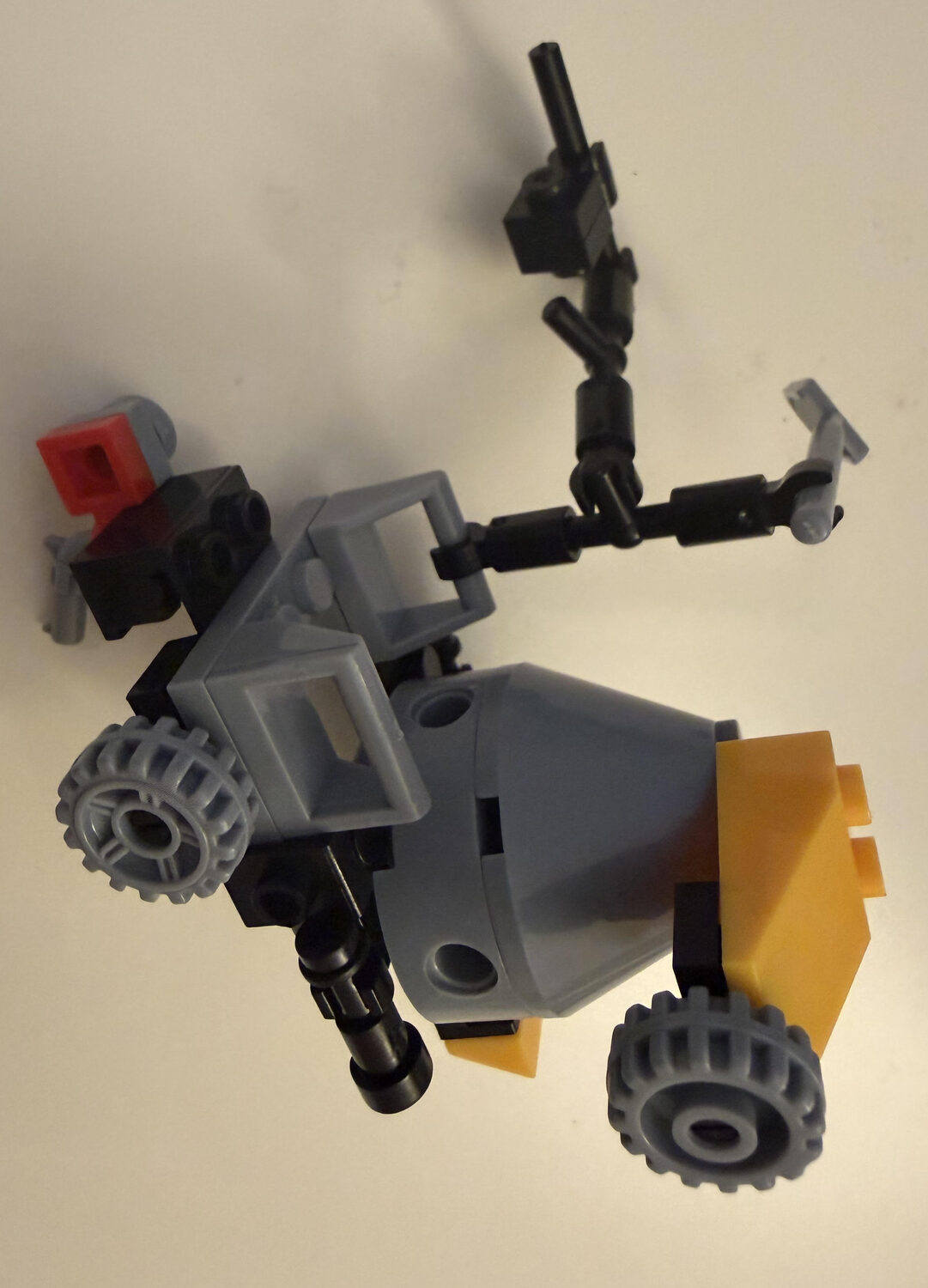 A Lego model designed and built by Aadi: a grey and black space station on two large wheels, with a cone-shaped body and a long jointed arm ending in a claw for catching space debris.