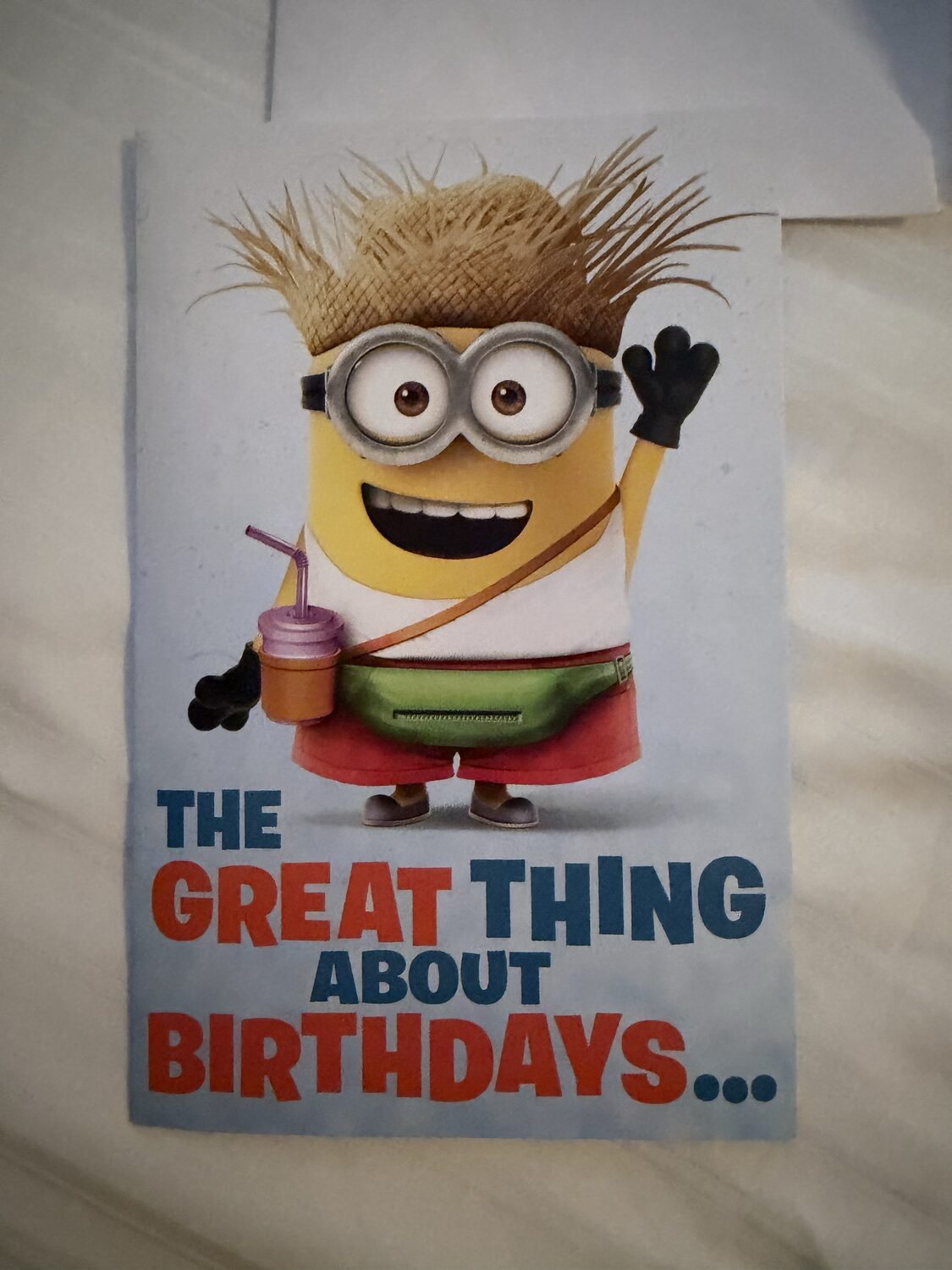 Birthday card front showing a Minion in a straw hat holding a drink, with the text 'The great thing about birthdays…'